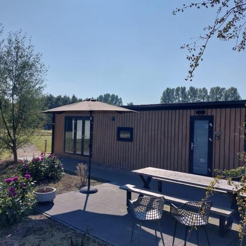 a picnic table and chairs in front of a cabin at De Eend - Tiny house in de Zeeuwse Natuur in Driewegen