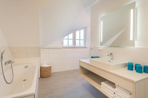 レーメにあるFerienhaus Uhlenhorstの洗面台とバスタブのある白いバスルーム
