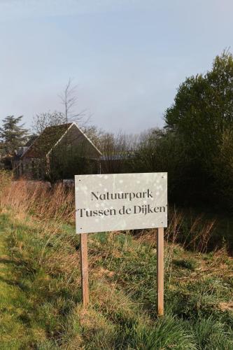 a sign in the grass next to a field at De Eend - Tiny house in de Zeeuwse Natuur in Driewegen