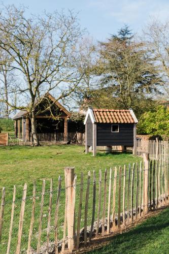 a small house in a field behind a fence at De Eend - Tiny house in de Zeeuwse Natuur in Driewegen