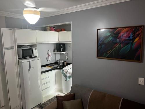 a kitchen with a white refrigerator and a microwave at Apto 1 dorm - San Francisco - localização perfeita in Balneário Camboriú