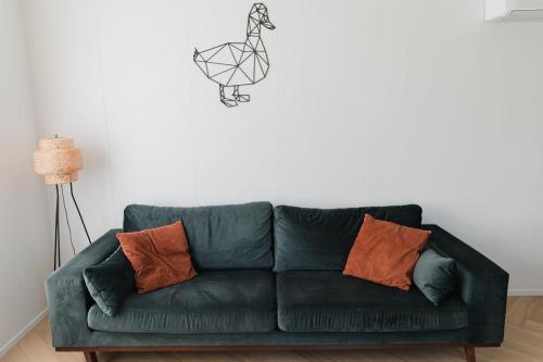 a green couch with orange pillows in a living room at De Eend - Tiny house in de Zeeuwse Natuur in Driewegen