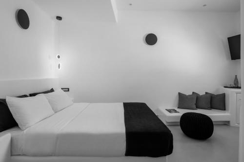 a white bedroom with a large bed and a couch at Tataki Family Hotel in Fira