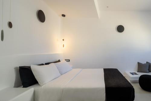 a bedroom with a large white bed with white pillows at Tataki Family Hotel in Fira