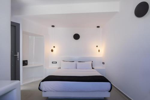 a white bedroom with a bed with white walls at Tataki Family Hotel in Fira