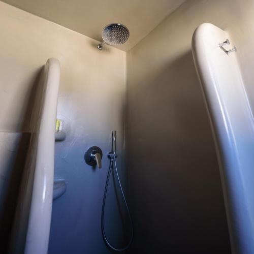 a bathroom with a shower with a hose in it at Tataki Family Hotel in Fira