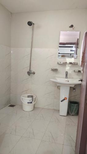 a white bathroom with a sink and a toilet at Aangan Residences in Skardu
