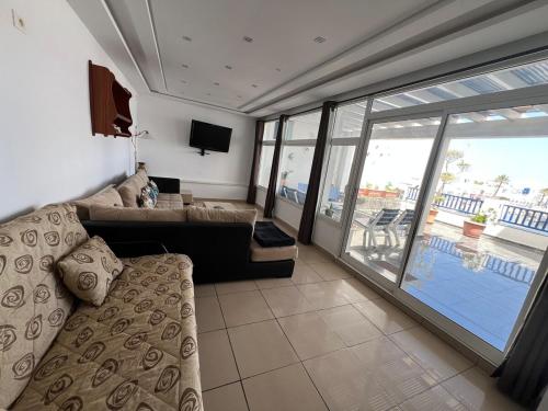 a living room with a couch and a tv and a balcony at Duplex Monastir avec terrasse sur la marina in Monastir