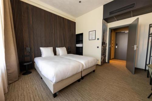 a bedroom with a large bed with white sheets and pillows at Flonk Hotel Groningen Centre, BW Signature Collection in Groningen