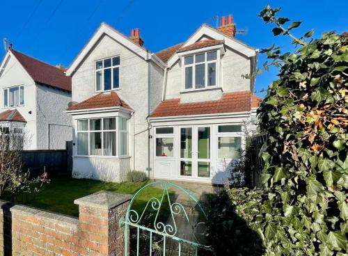 a white house with a gate in front of it at 5 Bed Villa - Sleeps 10 - Pets - Garden - Parking in Skegness