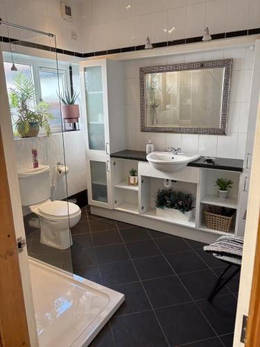 a bathroom with a sink and a toilet and a mirror at 5 Bed Villa - Sleeps 10 - Pets - Garden - Parking in Skegness