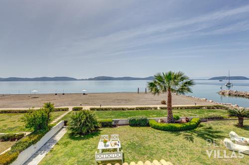a park with a beach and a palm tree at Beachfront Villa Armonia in Porto Hydra by goutos properties in Ermioni