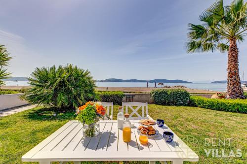 a picnic table with food on it with a view of the beach at Beachfront Villa Armonia in Porto Hydra by goutos properties in Ermioni