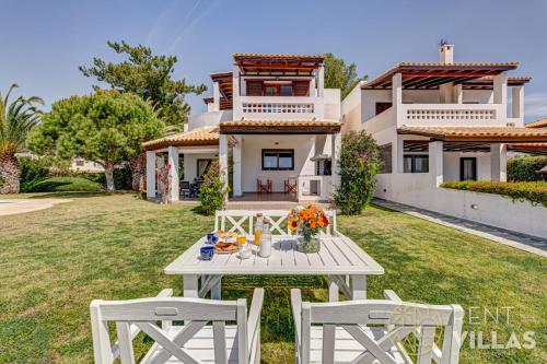 a view of a house with a table and two chairs at Beachfront Villa Armonia in Porto Hydra by goutos properties in Ermioni
