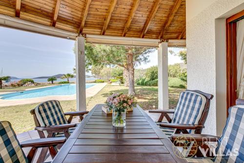 a wooden table with chairs and a vase of flowers at Beachfront Villa Armonia in Porto Hydra by goutos properties in Ermioni