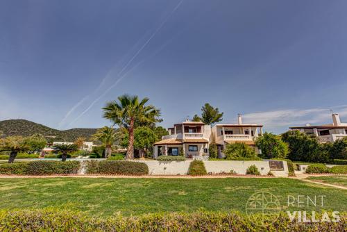 a house with a lawn and palm trees at Beachfront Villa Armonia in Porto Hydra by goutos properties in Ermioni
