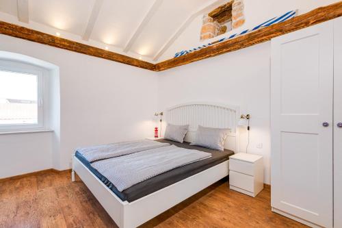 a white bedroom with a bed and a window at Kuća Koza-Apartment Elisa in Punat