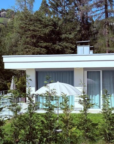 a white house with an umbrella in front of it at Chalet Tschattlhof Dolomites in Ponte Nova