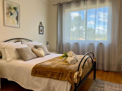 a bedroom with a bed with pillows and a window at Golf and Beach Serenity in Aroeira