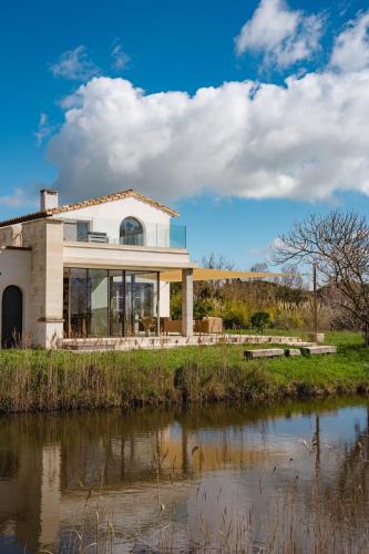a house next to a body of water at Mas du Couvin, maison d'hôtes en Camargue in Saintes-Maries-de-la-Mer