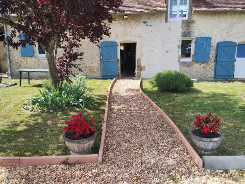 a garden with two flower pots and a house at Le paradis des chats bercéen chez Stéphanie près circuit du Mans, animaux acceptés in Marigné-Laillé