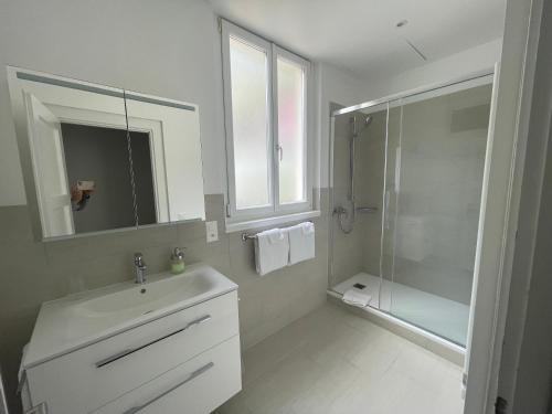 a white bathroom with a sink and a shower at Art Hotel Ristorante Posta Al Lago in Ronco s/Ascona - Porto Ronco