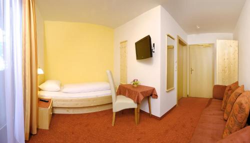 a room with a bed and a table with a chair at Hotel - Restaurant Platzwirt in Rauris