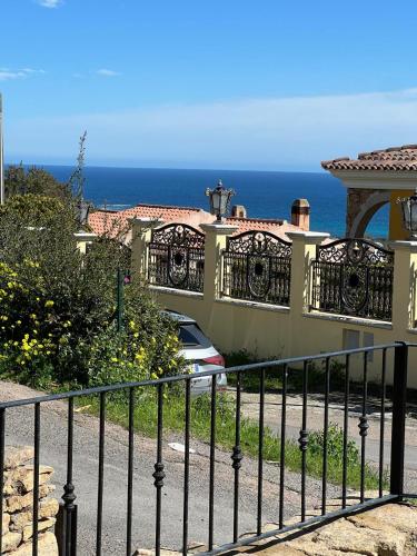 a fence in front of a house with the ocean at Casa Arborea in Agrustos