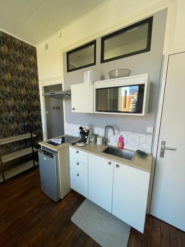 une cuisine avec des armoires blanches et un évier dans l'établissement Opale 3, à Vichy