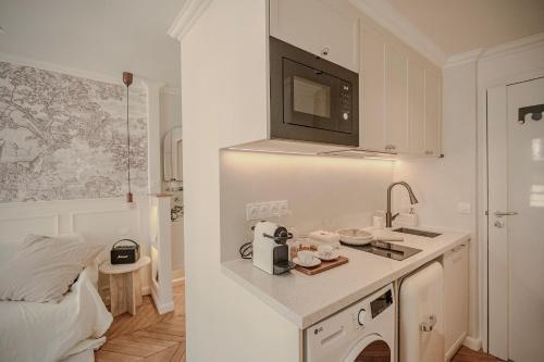 une cuisine blanche avec un évier et un micro-ondes dans l'établissement Appartement Opéra centre Paris, à Paris