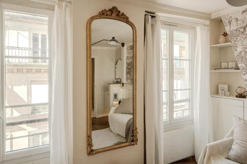 un miroir dans une pièce à côté d'une fenêtre dans l'établissement Appartement Opéra centre Paris, à Paris