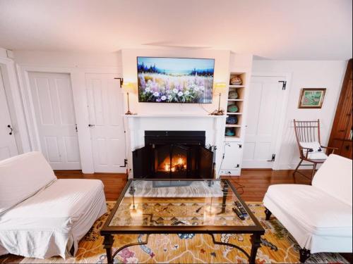 a living room with a fireplace with a tv above it at Capt Clarke Historic Homestead Venue in Old Saybrook
