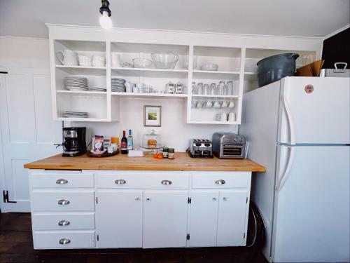 a kitchen with white cabinets and a white refrigerator at Capt Clarke Historic Homestead Venue in Old Saybrook