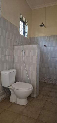 a bathroom with a white toilet and a window at Eagle Nest lake Natron Guest House in Mtowabaga