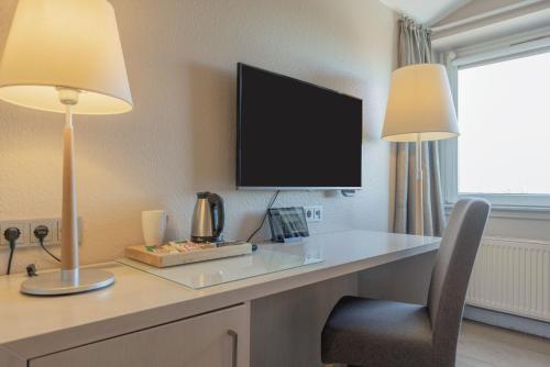 a desk with a television and a chair in a room at Best Western Plus Theodor Storm Hotel in Husum