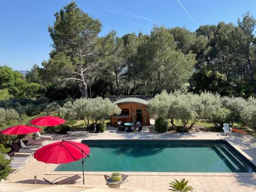 une piscine avec deux parasols et une maison dans l'établissement Appel du Luberon, à Mérindol