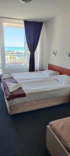 a bedroom with a large bed with a large window at Hotel Arda in Sunny Beach