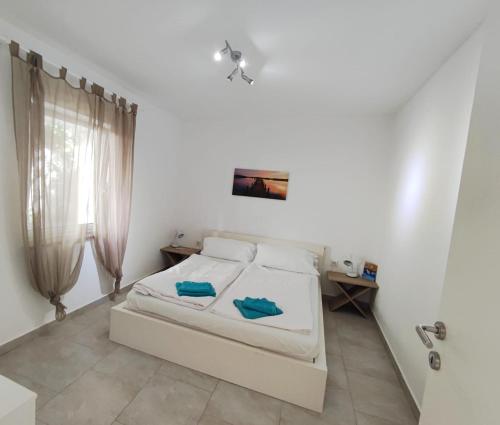 a white bedroom with a bed and a window at Olcsica Apartment in Klenovica
