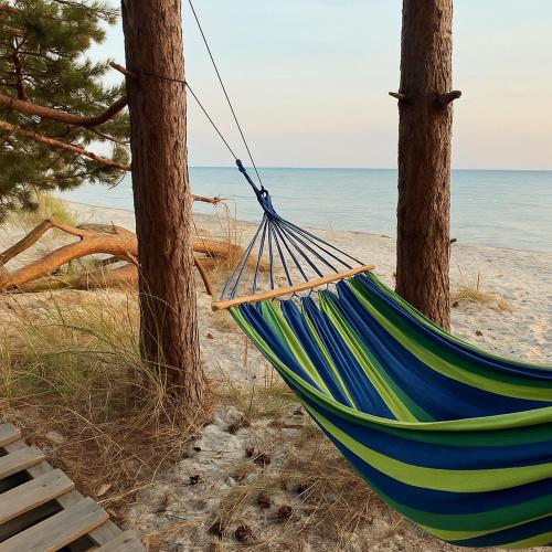 a hammock hanging from two trees on the beach at Przyczepa kempingowa in Hel