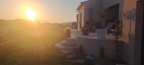 a sun setting behind a building with steps in front at Le Bonheur à Ventoux in Saint-Pierre-de-Vassols