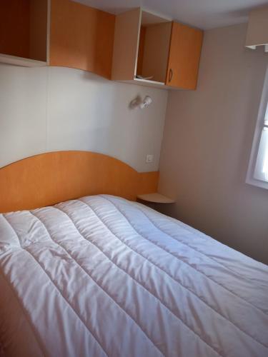 une chambre avec un lit blanc avec une tête de lit en bois dans l'établissement L'évasion, à La Bernerie-en-Retz