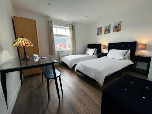 a room with two beds and a desk with a lamp at Stay in City Centre 1 in Belfast