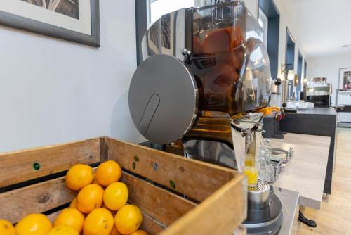 a pile of oranges in a wooden box next to a juicer at Best Western Plus Theodor Storm Hotel in Husum
