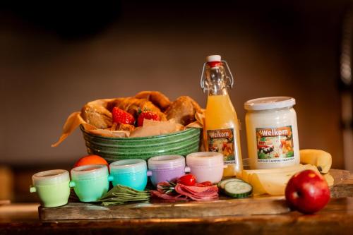 einen Tisch mit einem Korb Brot und einer Flasche Saft in der Unterkunft Boerderij Camping NixHoeve in Genderen