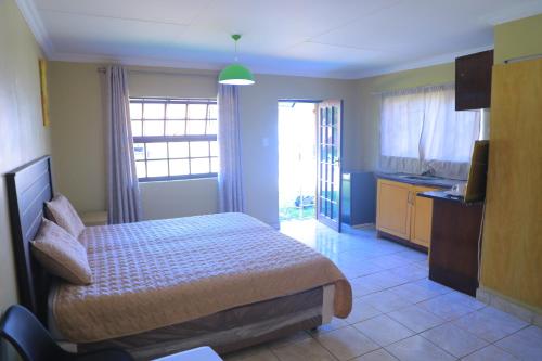 a small bedroom with a bed and a kitchen at Ivy at 6 Peace Sleep in Pretoria