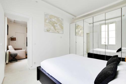 une chambre blanche avec un lit et un miroir dans l'établissement Beautiful Apartment Marais Bastille, à Paris