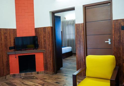 um quarto com uma televisão, uma cadeira e uma porta em The Vintage Haven Munnar em Devikolam