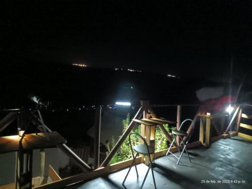 a deck at night with two chairs and lights at Hostal Vista hermosa del Páramo alto, Laguna Verde in Valparaíso