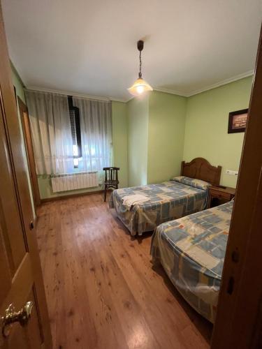 two beds in a room with green walls and wooden floors at Hotel Rural El Puente in Mansilla de las Mulas