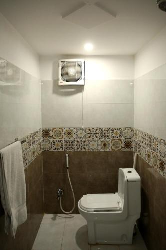 a bathroom with a toilet and a air conditioner at Royalton Inn Hotel - Liberty in Lahore
